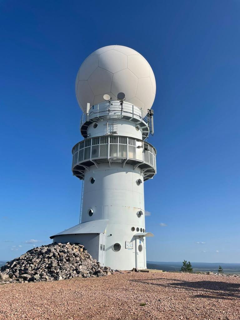 Kuva valkoisesta rakennuksesta tunturin huipulla. Lieriön mallisen rakennuksen päällä on jalkapallon kaltainen pyöreä osa.