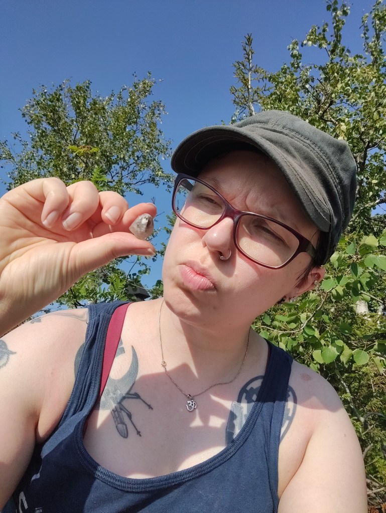 Selfie Katjasta, joka tarkastelee sormiensa välissä pitelemäänsä ametistia.