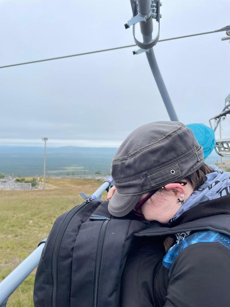 Kuva Katjasta hississä. Katha on painanut naamansa reppuun, ettei näe maisemia.