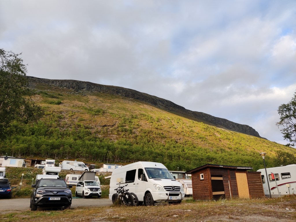 Kuva tunturin juurelle parkkeeratuista lukuisista asuntoautoista.