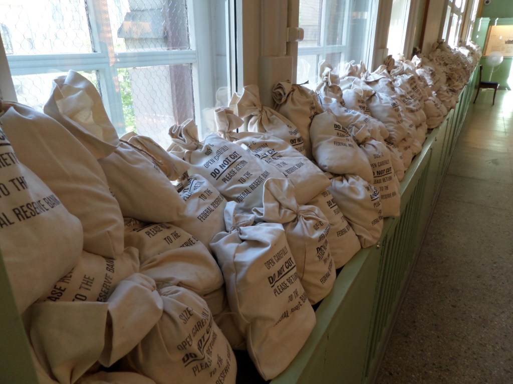 Kuva pitkästä ikkunapöydästä, joka on tupaten täynnä kankaisia pussukoita, joissa on ollut aikoinaan rahaa.