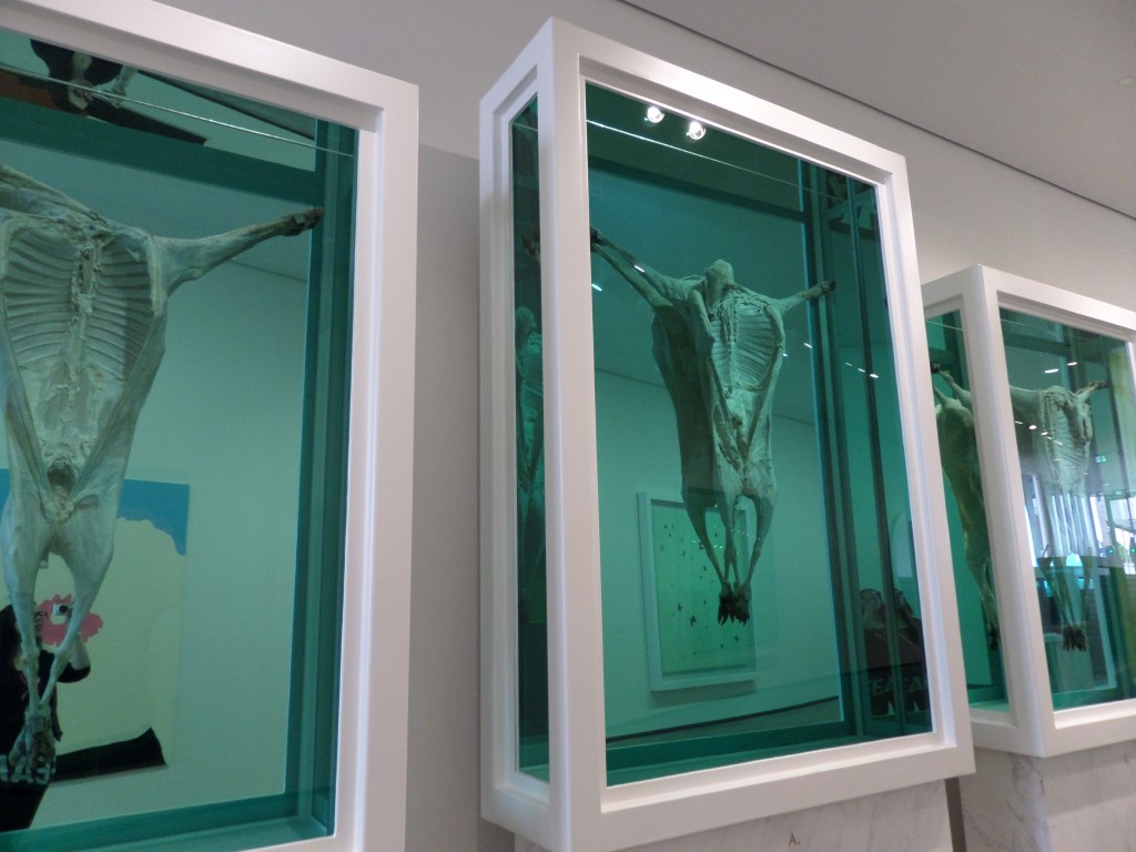 Kuva, jossa esillä kaikki kolme valkokehyksistä taideteosta, joissa on ristiinnaulittujen lampaiden ruhoja.