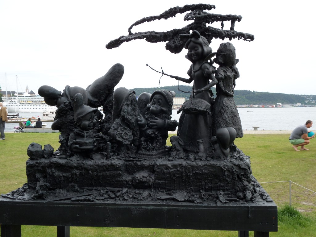 Kuva ulkona olevasta veistoksesta, jossa on kuvattu Lumikki ja seitsemän kääpiötä. Hahmot on tehty Disney-elokuvan hahmojen näköisiksi, mutta niissä on jotain pielessä: kasvot saattavat olla pelkkää valuvaa massaa tai silmät puuttua kokonaan.