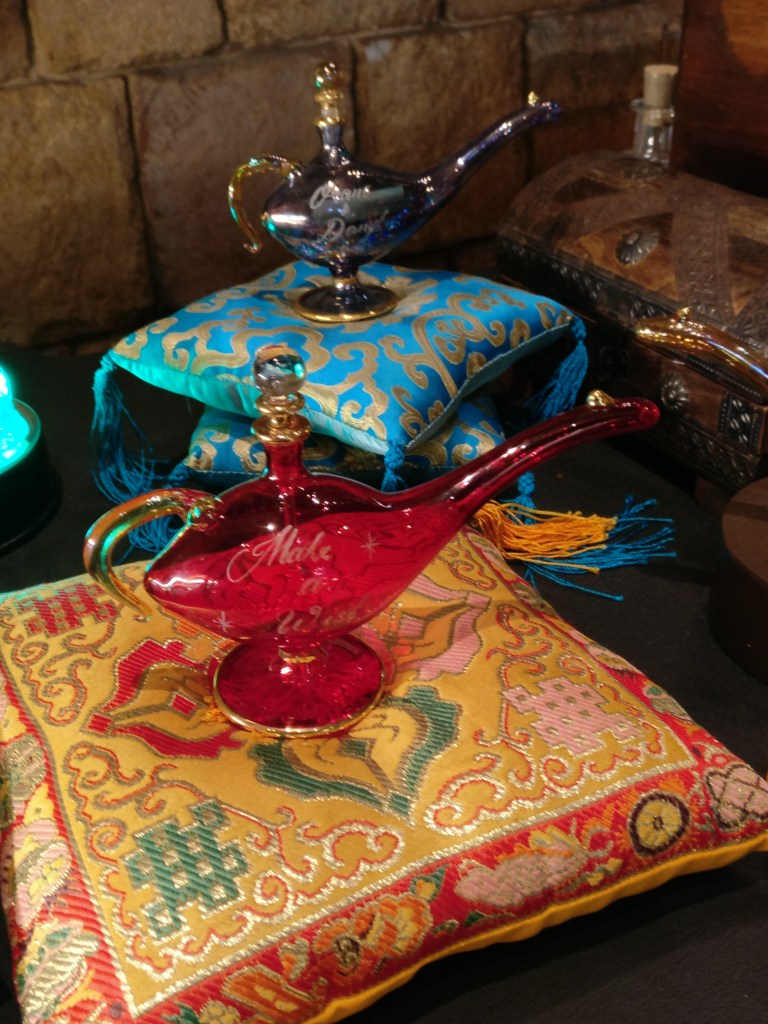 Kaksi tyynyille asetettua lasista Aladdinin taikalamppua.