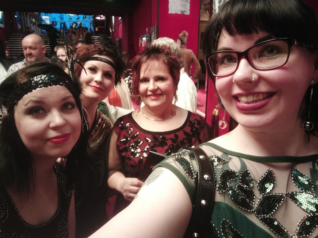 Ryhmäselfie, jossa itseni lisäksi ovat kaksi siskoani sekä äitini. Meillä on kimaltelevat, 1920-luvun henkiset mekot yllämme.