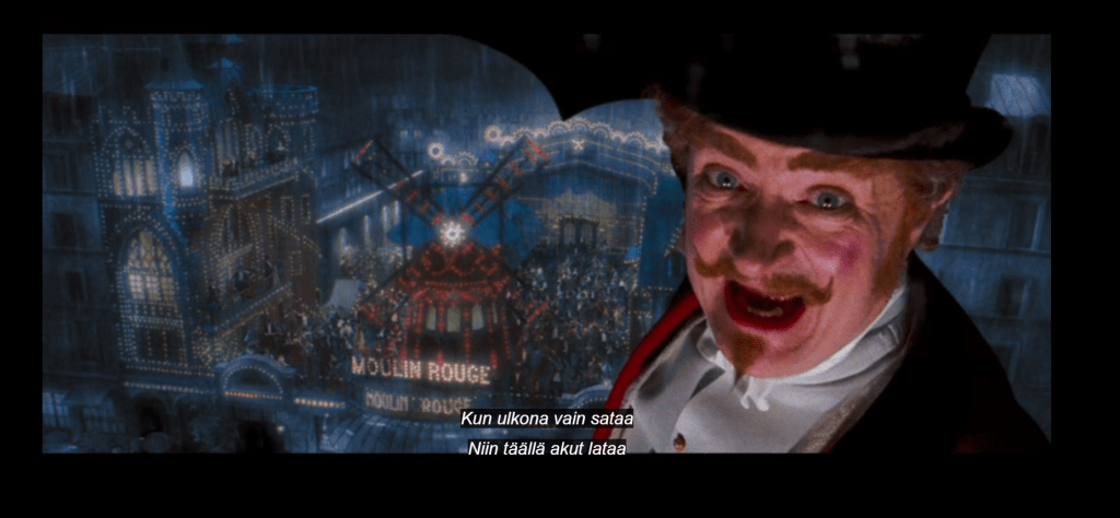 Kuvakaappaus Moulin Rouge -elokuvasta, jossa esitellään lähikuvassa myllyn omistaja Harold Zidler. Taustalla näkyy sateessa kirkkaana hehkuva Punainen Mylly.