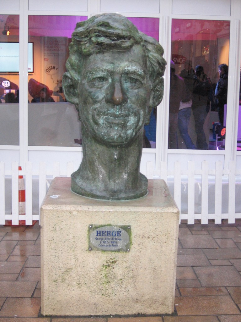 Lähikuvassa sarjakuvataiteilija Hergén patsas, joka on vain hänen päänsä matalalla jalustalla.