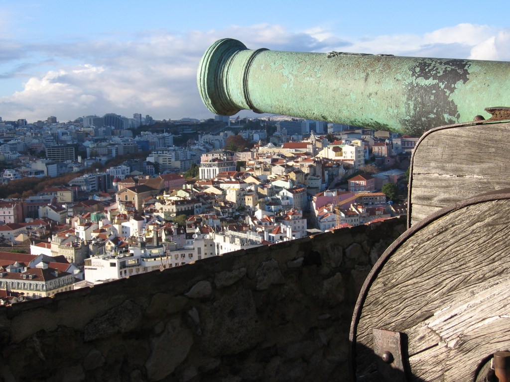 Erikoislähikuva tykin suusta, jonka takaa näkyy Lissabonin kaupunkia.