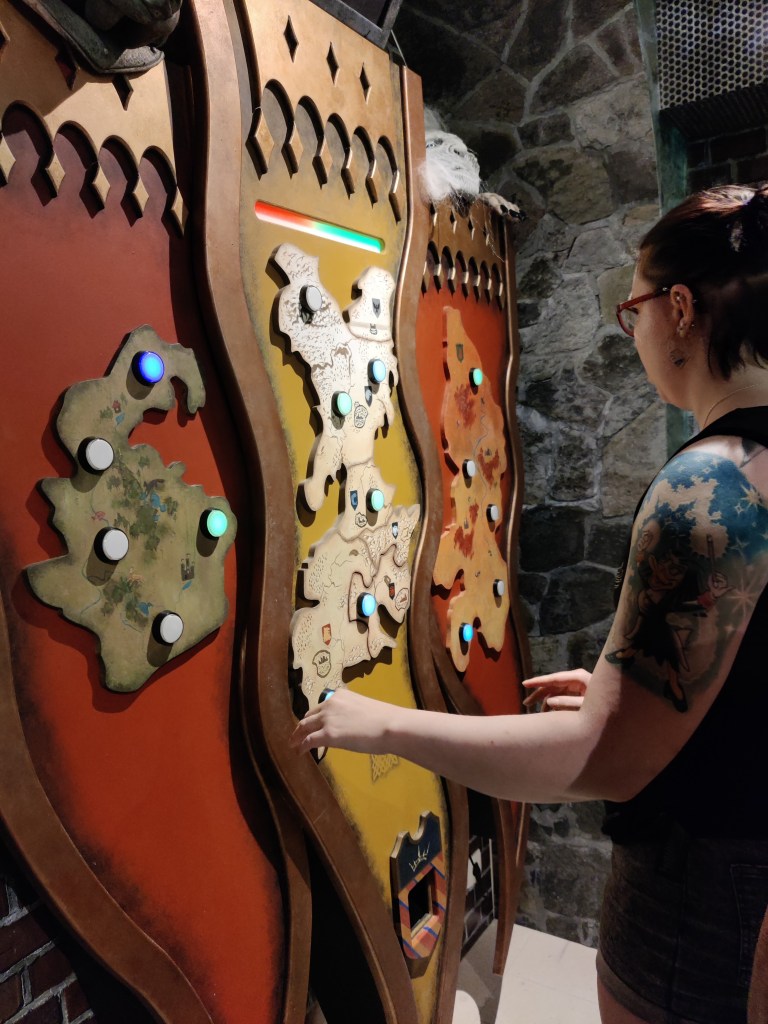 Kuvassa Katja pelaa seinällä olevaa kartan malliin rakennettua muistipeliä, jossa pitää muistaa värivalojen järjestys.