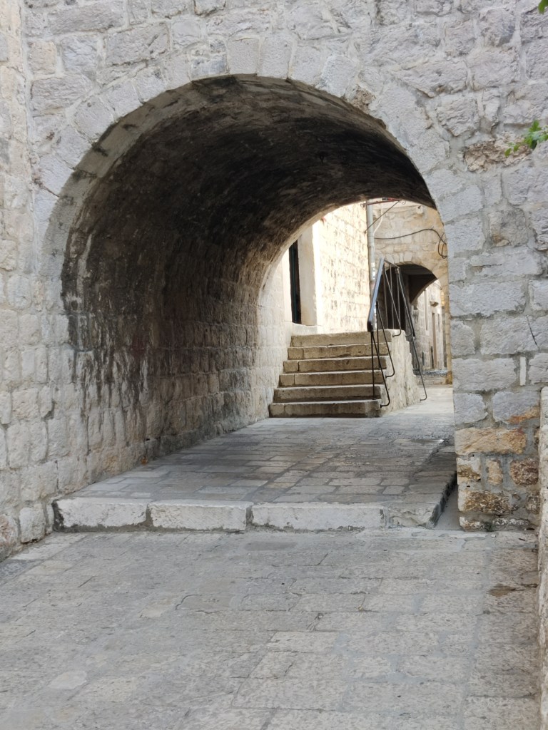 Kuvassa kivinen, pyöreä aukko paksussa muurissa ja sen takana kiviset portaat oviaukolle.