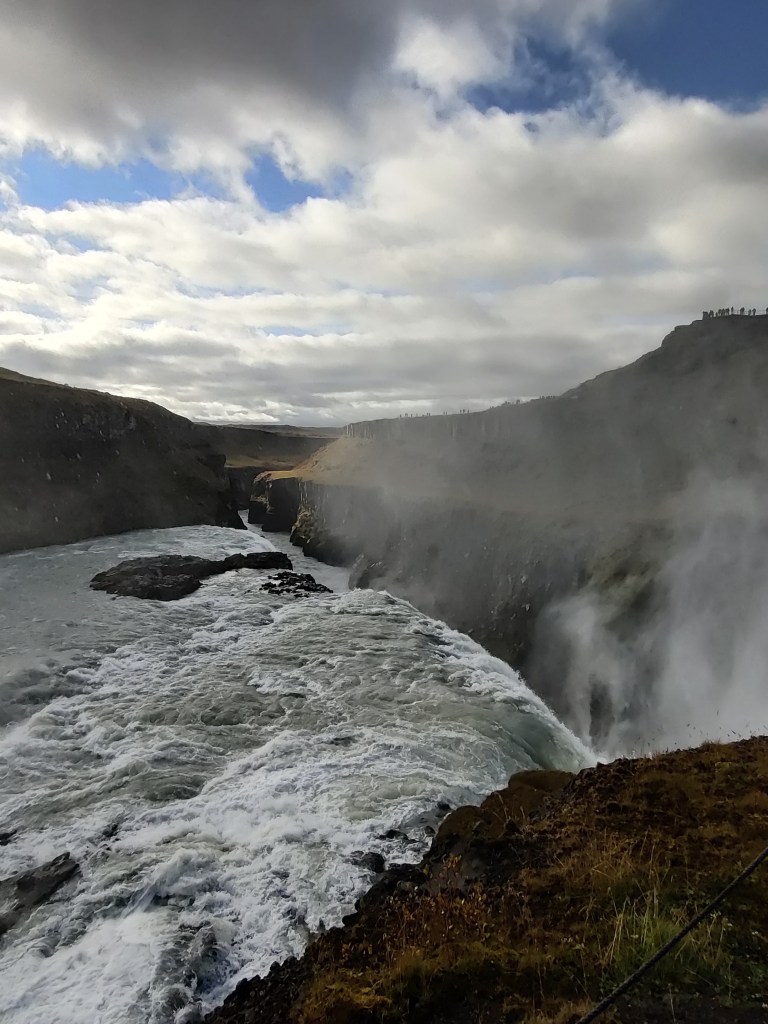 Kuva vesiputouksen huipulta, jossa vesi putoaa alas näkymättömiin. Vain höyry nousee.