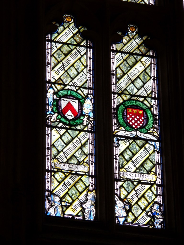 Lähikuva lasimaalausikkunoista, joiden alareunassa ainakin Herttakuningatar ja valkoinen kani.