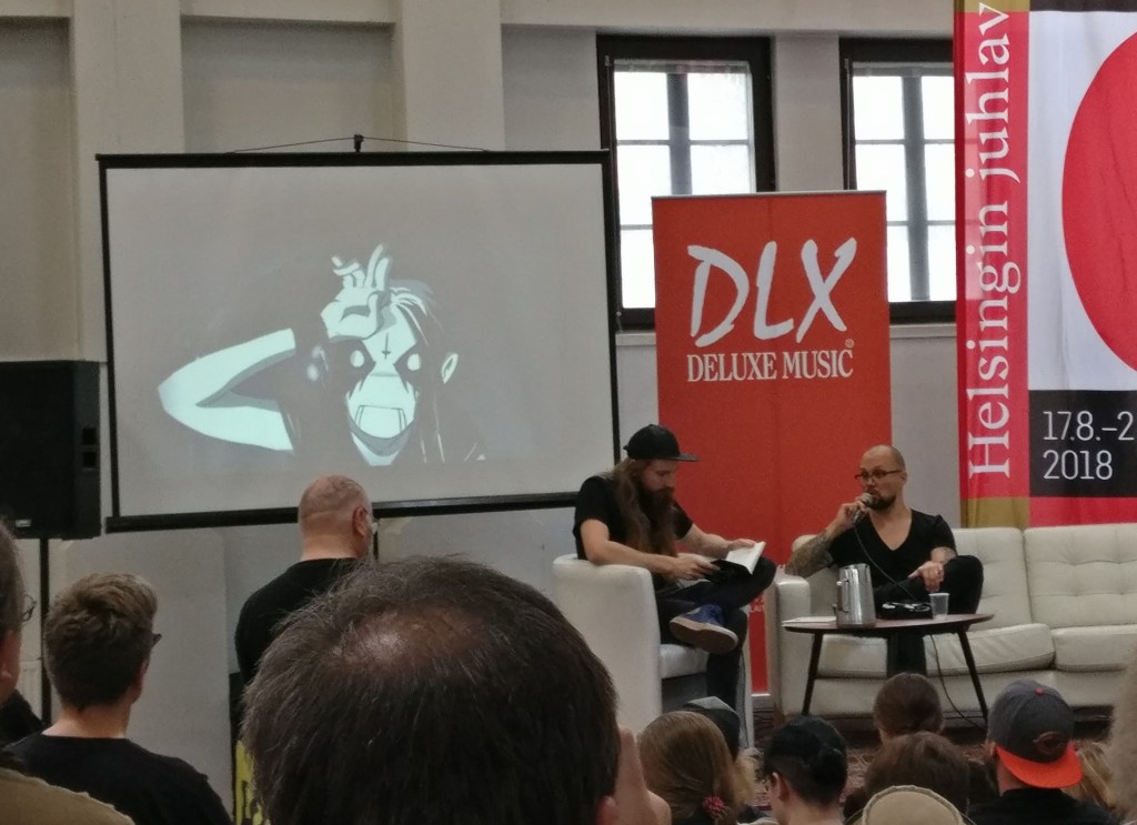 JP Ahonen Helsingin sarjakuvafestareiden haastattelussa 2018. Taustalla isossa kuvaruudussa Sloth-hahmo Belzebubs-sarjakuvasta.