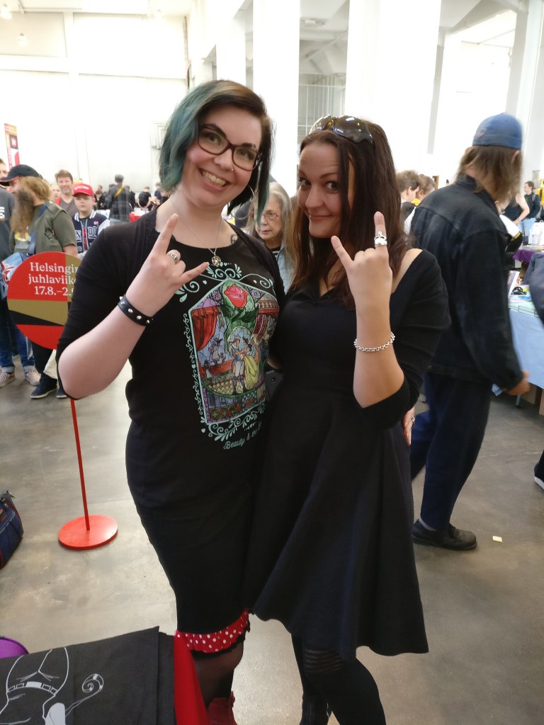 Katja ja Lise Myhre poseeraavat vierekkäin hevikäsimerkein Helsingin sarjisfestareilla.