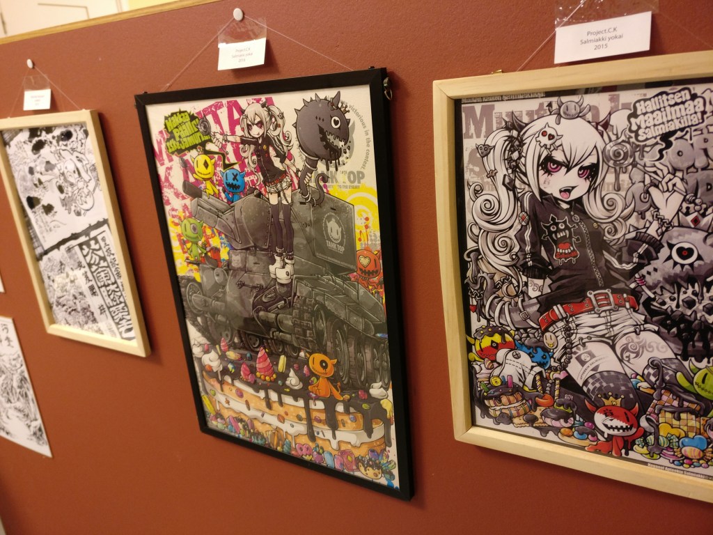 Kaksi mangahengistä taulua, joissa vaaleatukkaisella tytöllä pitkät saparit ja tuimat silmät. Värikkäissä kuvissa muun muassa tankki jättimäisen kakun päällä.