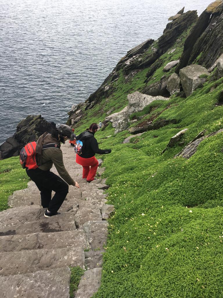Kuva kivirappusista, jotka laskeutuvat alas jyrkkää rinnetta vihreän kasvillisuuden keskellä. Katja ja Tuula laskeutuvat rappusia alas kovin varoivaisesti sivuttain.