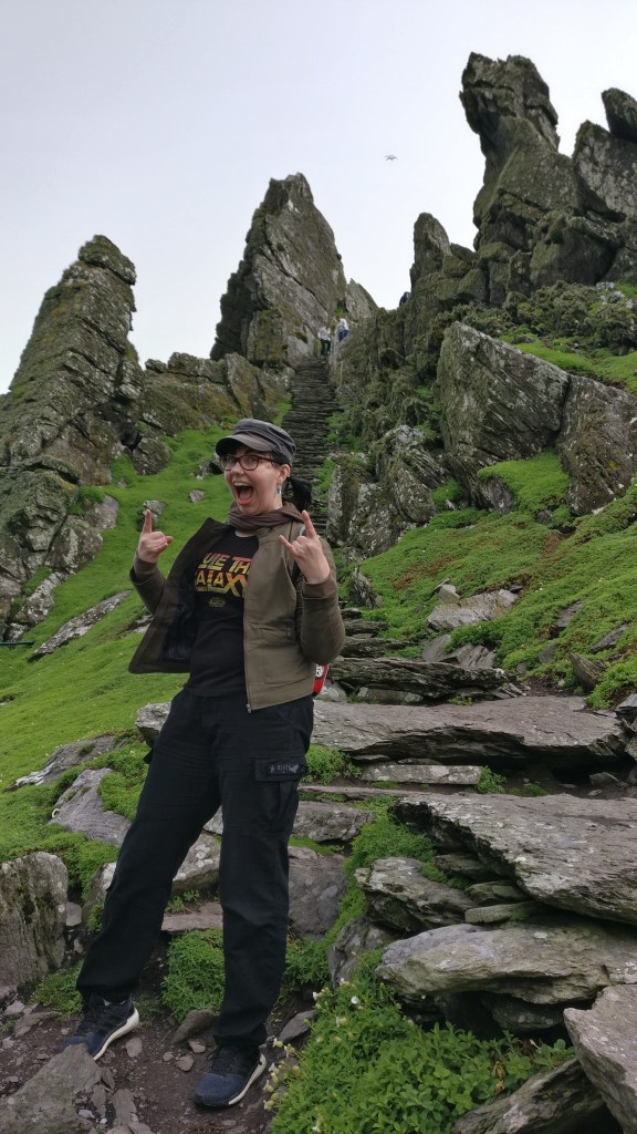 Kokovartalokuva Katjasta, joka poseeraa innoissaan kivikkoisen rinteen juurella. Isojen kivipaasien väliin vievät luonnonmukaiset kiviportaat.