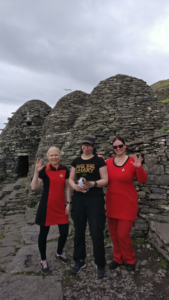 Yhteiskuva kolmesta reissaajasta, keskellä Katja Star Wars -puserossaan, kummallakin puolella punaisissa Star Trek -asuissaan poseeraavat ystävät tekemässä vulkanilaista tervehdystä.