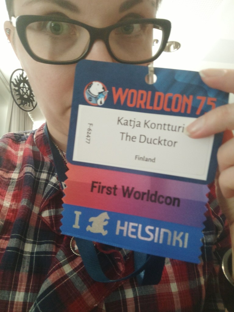 Selfie Katjasta, joka esittelee Worldcon-badgeaan, jossa lukee oma nimi ja alla nauhat "First Worldcon" ja "I (jääkarhu) Helsinki"