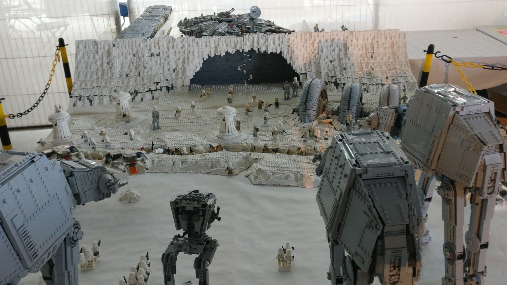 Kuva Lego-setistä, jossa on rakennettu uudelleen Imperiumin vastaisku -elokuvan taistelukohtaus, jossa isot AT-AT-talsijat hyökkäävät kapinallisten piilopaikkaan jääplaneetalla. Taustalla näkyy Millennium Falcon -alus.