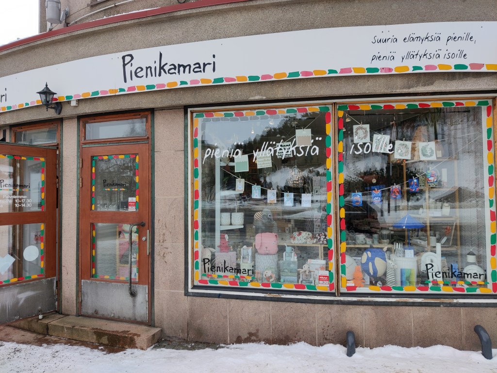 Pienikamarin näyteikkuna. Ikkunan yläpuolella lukee "suuria elämyksiä pienille, pieniä yllätyksiä isoille".