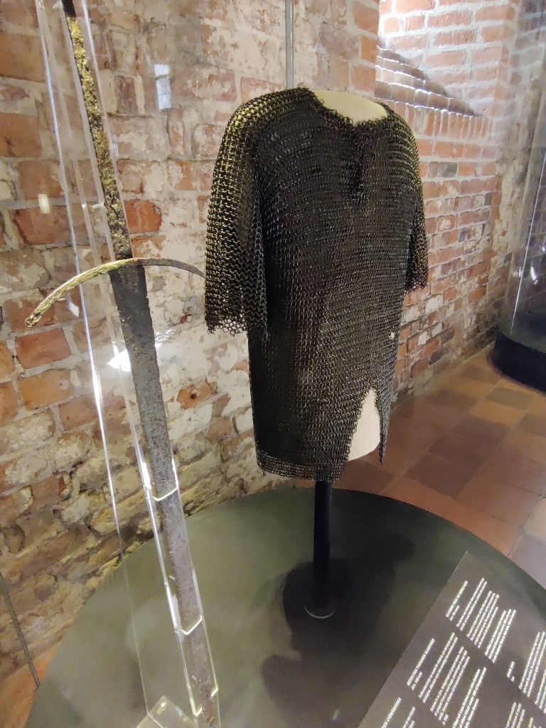 Kuvassa mallinuken päällä oleva rengaspaita ja pitkä kahden käden miekka.