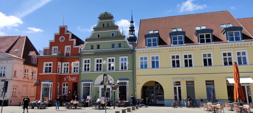 Kuvassa kolme eriväristä,julkisivultaan persoonallista taloa: punainen, vihreä ja keltainen. Punaisen ja vihreän talon julkisivut kapenevat porrastetusti ylöspäin.