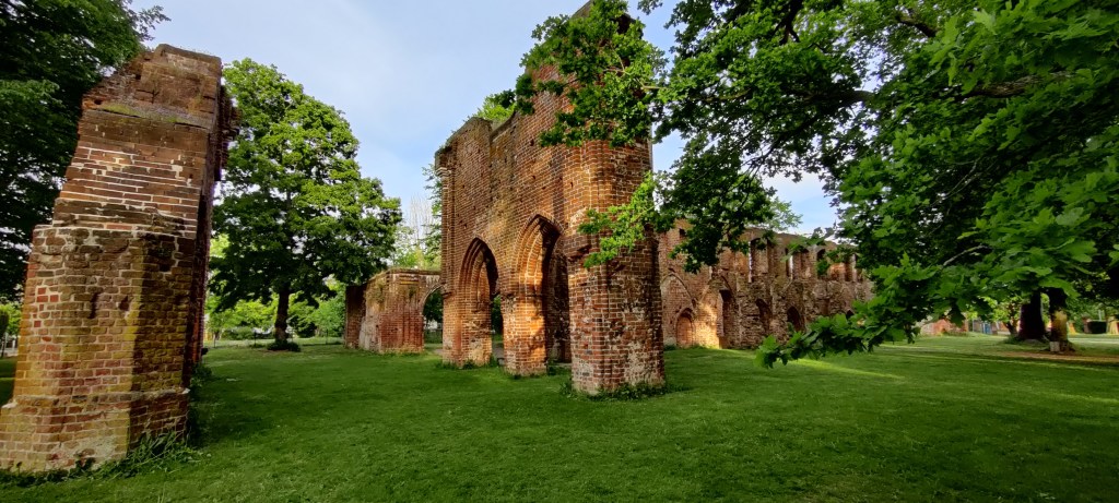 Laaja kuva punatiilisistä, massiivisistä raunioista, joissa korkeita, pyöreitä holvikaaria. Rauniot ovat vihreän nurmen päällä. Ympärillä paljon puita.