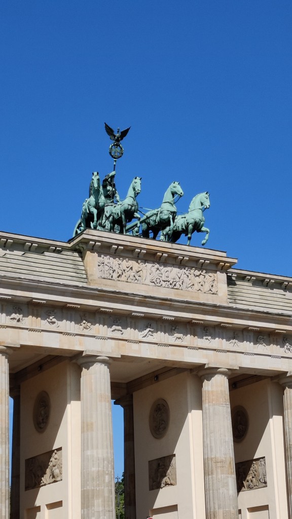 Kreikkalaistyylinen portti: korkeat doorilaiset pylväät kannattelevat katosta, jonka päällä seisoo neljän hevosen vetämä valjakko. Valjakoissa voiton jumalatar pitelee kätessään sauvaa.