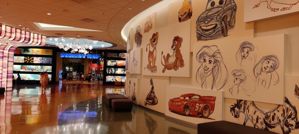 Kuva valtavasta aulatilasta, jonka oikea seinä on kaareva ja esittelee luonnosmaisia kuvia Pienestä merenneidöstä, Autoista ja Leijonakuninkaasta. Taustalla näkyy osa isoa kynttiläkruunua, jonka valo heijastuu kiiltävästä lattiasta. Aulassa on muutama matala sohva, muuten se on melko tyhjä.