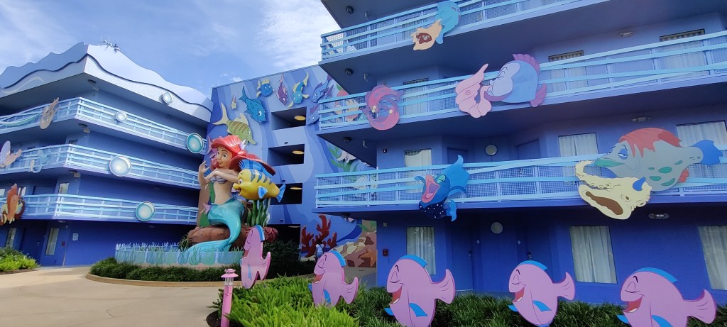 Art of Animation -hotellin Pieni Merenneito -siiven etuseinä, joka on koristeltu animaatiossa olevien kalojen kuvilla. Syvennyksesä on iso Arielin patsas, jossa mukana myös Pärsky-kala.