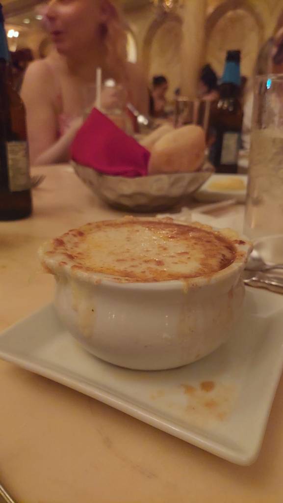 Lähikuvassa pyöreä kippo, jossa paahteisen näköinen juustokuorrute. Taustalla näkyy sämpylälautanen.