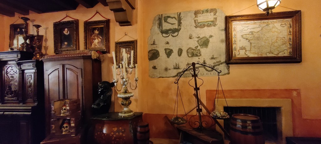 Kuvassa merirosvoajan henkeen teemoitellun kaupan sisustusta: isoja tummanruskeita kaapistoja, suuria kynttilänjalkoja ja raskaissa kehyksissä roikkuvia muotokuvia. Seinällä on myös kaksi isoa piirrettyä karttaa.