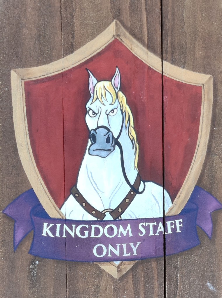 Erikoislähikuva ovessa olevasta kyltistä, joka muistuttaa vaakunaa. Kuvassa on Tangled-elokuvan Maximus-hevonen, jolla on tuima ilme. Kyltissä lukee "Kingdom staff only".