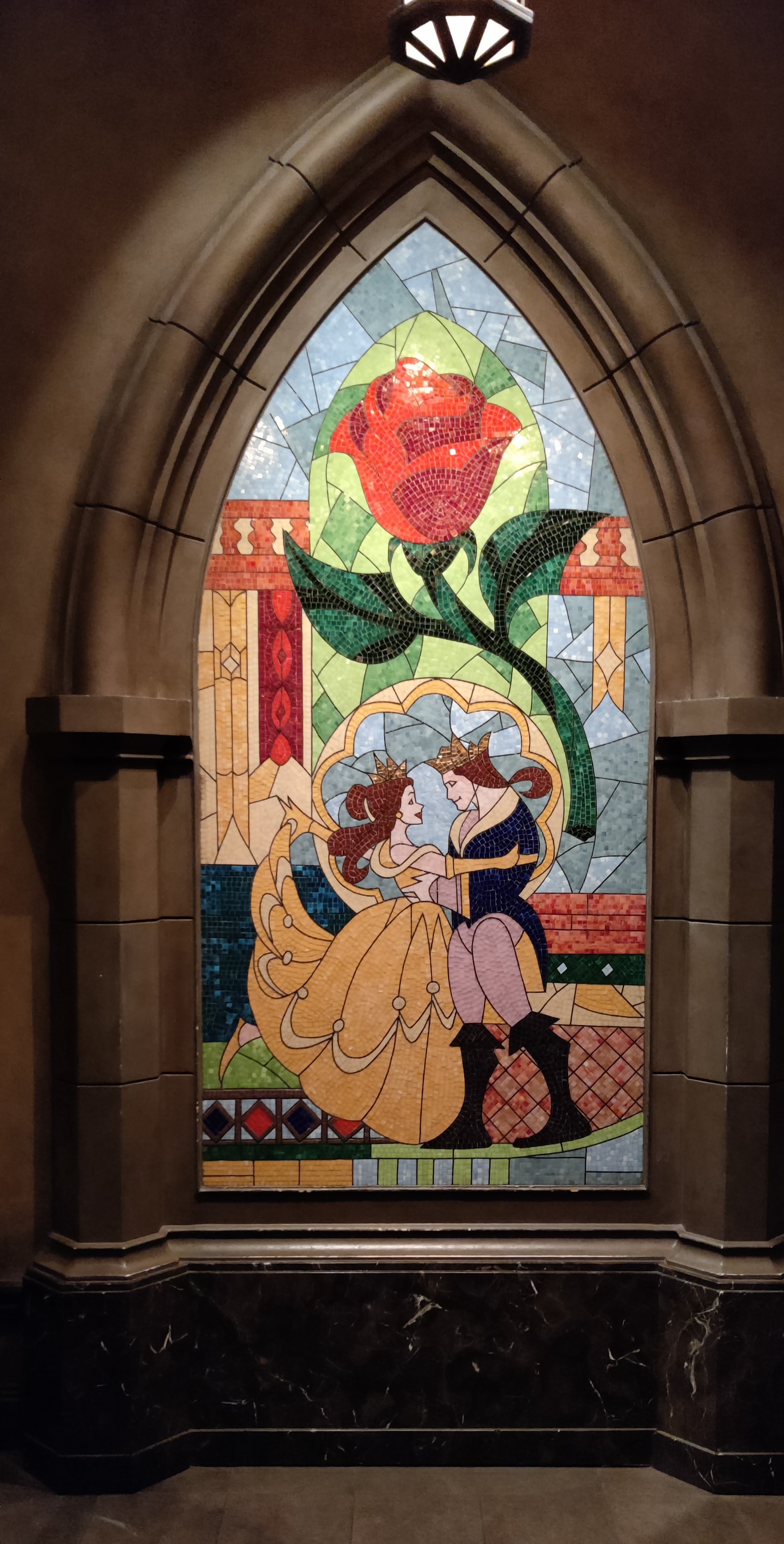 Kuvassa Kaunotar ja hirviö -elokuvan lopussa oleva lasimaalaus, jossa Belle tanssii ihmiseksi muuttuneen hirviön kanssa ja heidän yläpuolellaan on valtava punainen ruusu.