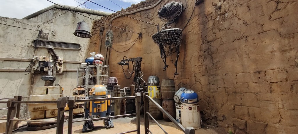 Tiilimuuerin edessä olevalla korokkeella on lukuisia erimallisia droideja. Imperiumin etsijä on nostettu seinälle verkossa.