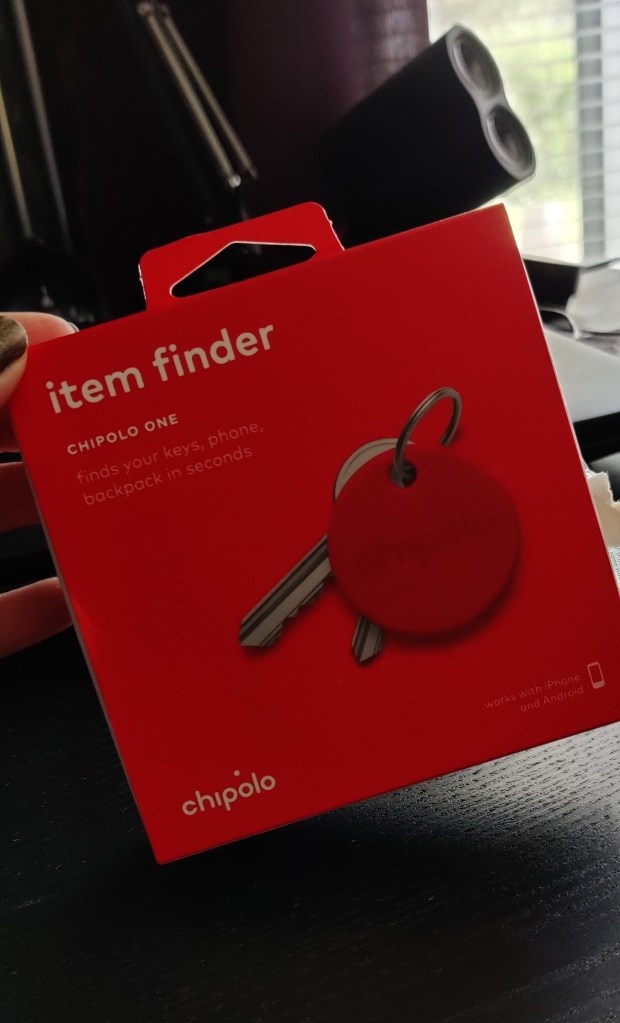 Kuvassa neliönmallinen punainen pieni pahvilaatikko, jossa lukee "item finder, Chipolo one - finds your keys, phone, backpack in seconds". Laatikon kannessa on kuva punaisesta kiekosta, joka on avaimenperänä kahdelle avaimelle.