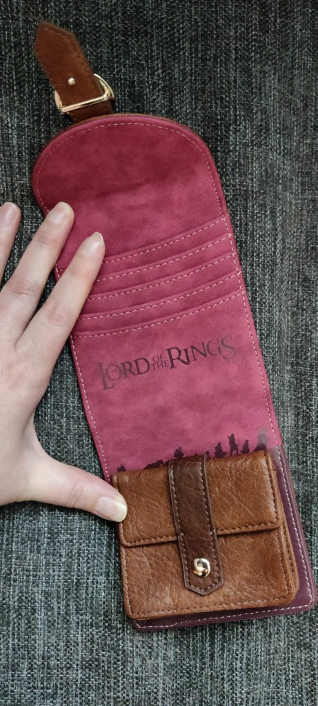 Avattuna lompakko leviää pituussuuntan ja paljastaa punertavan sisäosan. Siellä on paikat korteille ja elokuvista tuttu logoteksti Lord of the Rings. Alaosassa on pieni läpällä suljettava tasku kolikoille. Sen takaa erottuu sormusten saattueen silhuetit.