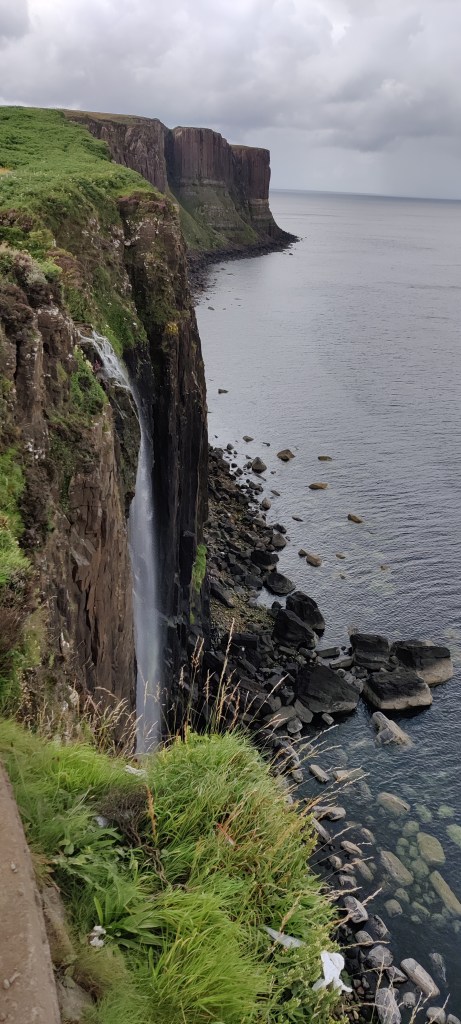 Ylhäältä kalliolta otettu kuva, jossa näkyy mereen laskeutuva vesiputous. Taustalla kallioinen ranta jatkuu pitkälle. Rannikko on karu ja kivinen.
