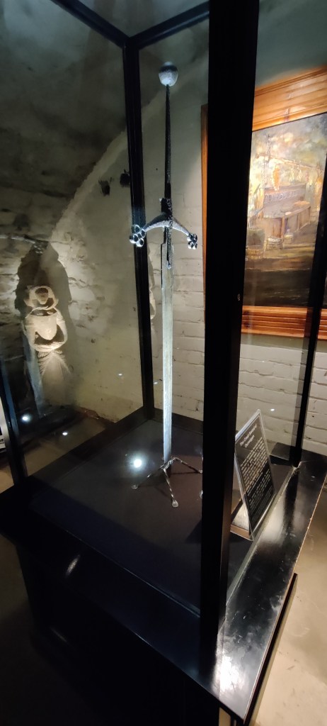 Korkeassa lasivitriinissä seisova kahdenkäden miekka.