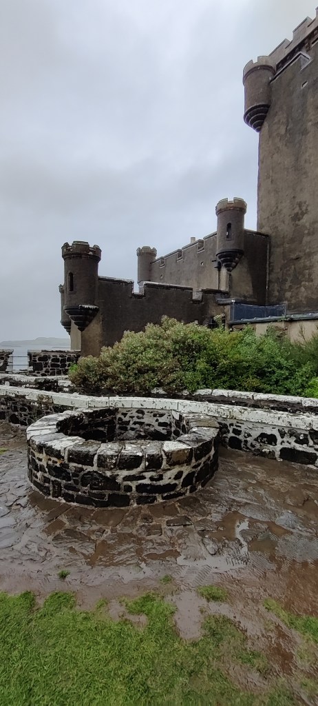 Linnanpihan pyöreä kaivo, jonka takana näkyy linnan puolustustornit.