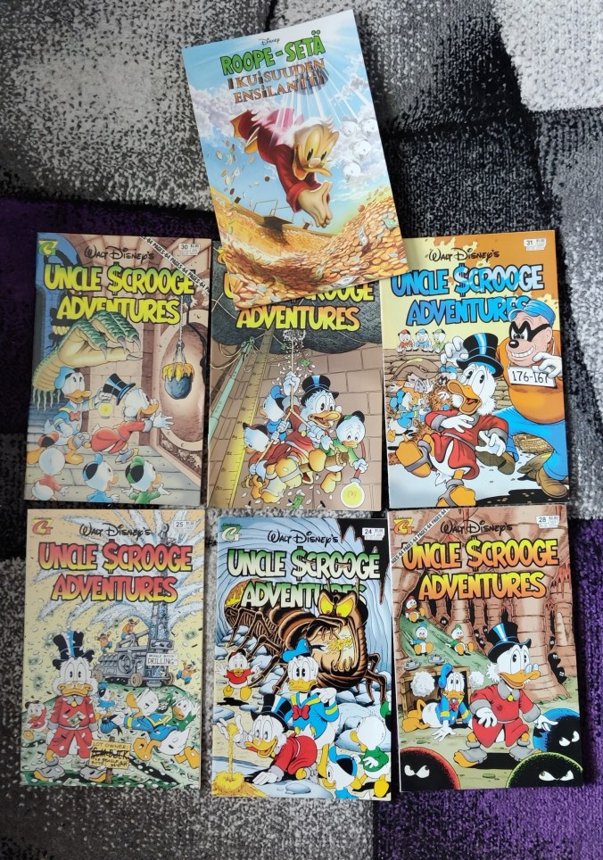 Lattialle aseteltu kuusi englanninkielistä Uncle Scrooge Adventures -sarjakuvalehteä, joiden kannet Don Rosa on piirtänyt. Ylimmäisenä on ihkauusi albumi Roope-setä ja ikuisuuden ensilantti.