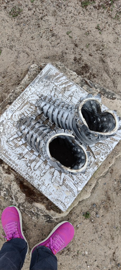 Yläviistosta otettu kuva patsaan yläpuolelta. Kengät näkyvät onttoina. Vieressä vertailun vuoksi Katjan violetit lenkkarit.