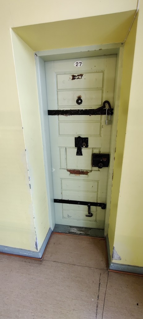 Syvennyksessä oleva ovi, jossa on useampi musta lukitusmekanismi ja pultti, joka vaatii avaamista, ennen kuin oven saa auki.