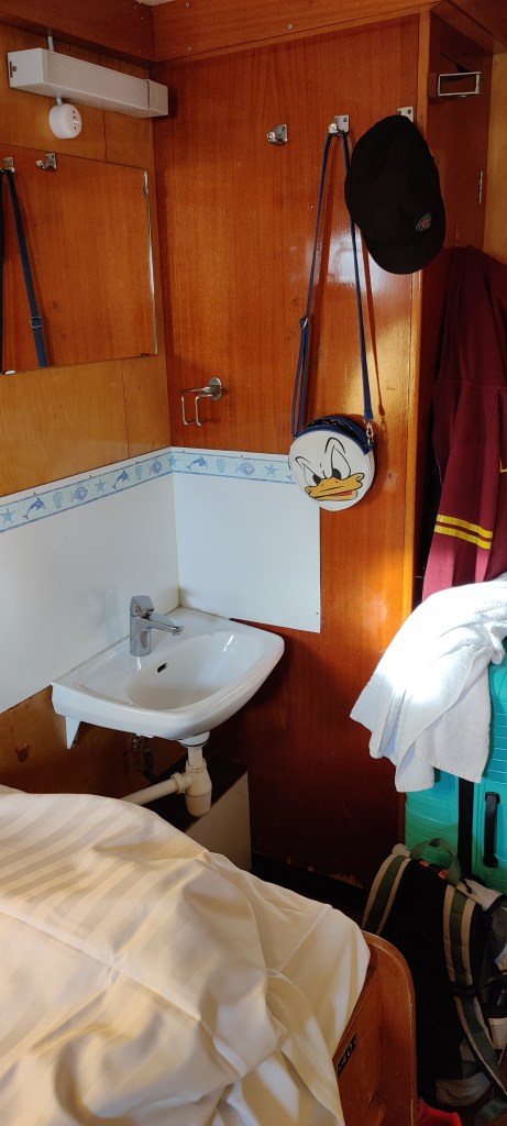 Hytin toinen nurkka: vaatekaapin edessä pieni lavuaari ja peili.