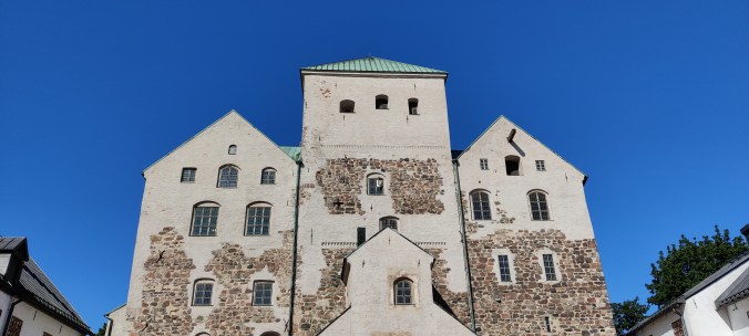 Kivisen linnan kolme tornia ikkunoineen sinistä, pilvetöntä taivasta vasten.