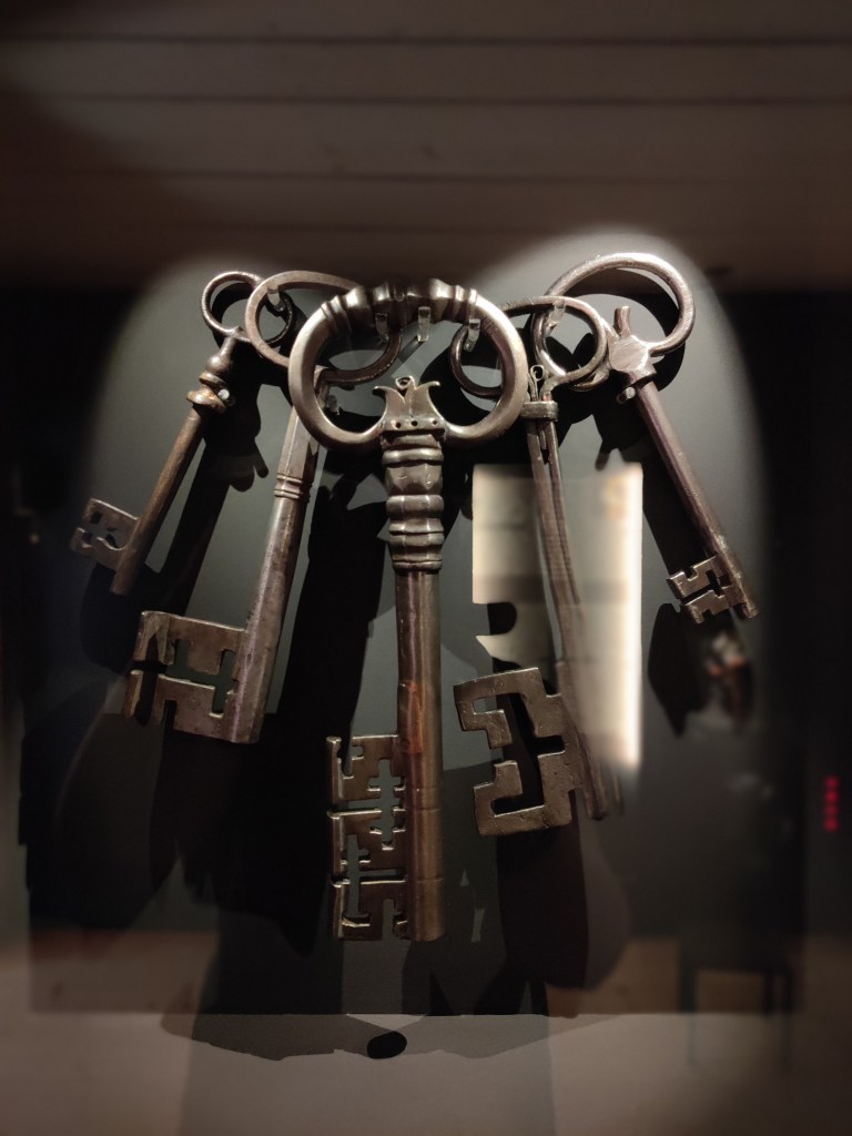 Erikoislähikuva vitriinissä roikkuvista vanhoista metalliavaimista.