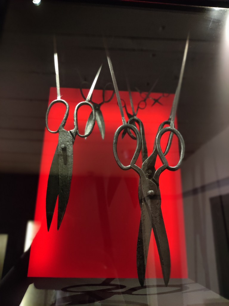 Erikoislähikuva vitriinissä roikkuvista vanhoista metallisaksista.