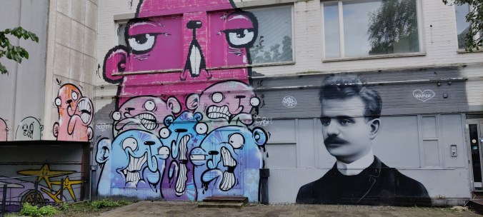 Graffitiseinä, jossa vasemmalla vaaleanpunaisia ja sinisiä isosilmäisiä jyrsijänkaltaisia olentoja ja oikealla varsin realistinen mustavalkoinen kuva Jean Sibeliuksesta.
